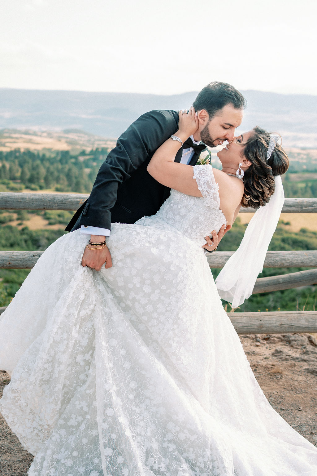 A groom dips his bride on a mountain overlook at sunset at Cielo At Castle Pines