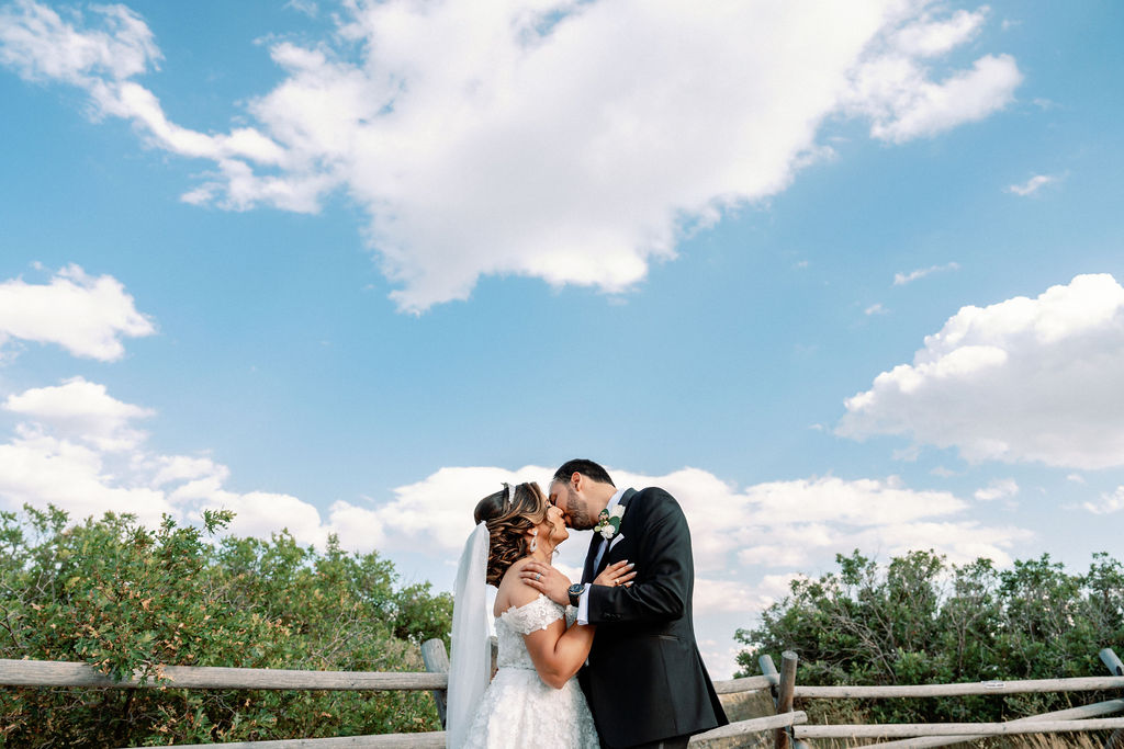 Newlyweds kiss under clear blue skies