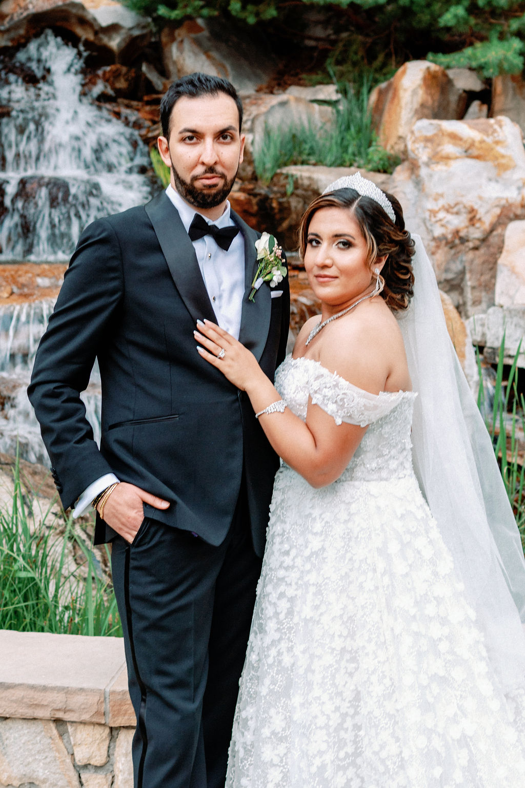A bride and groom stand by a waterfall at Cielo At Castle Pines