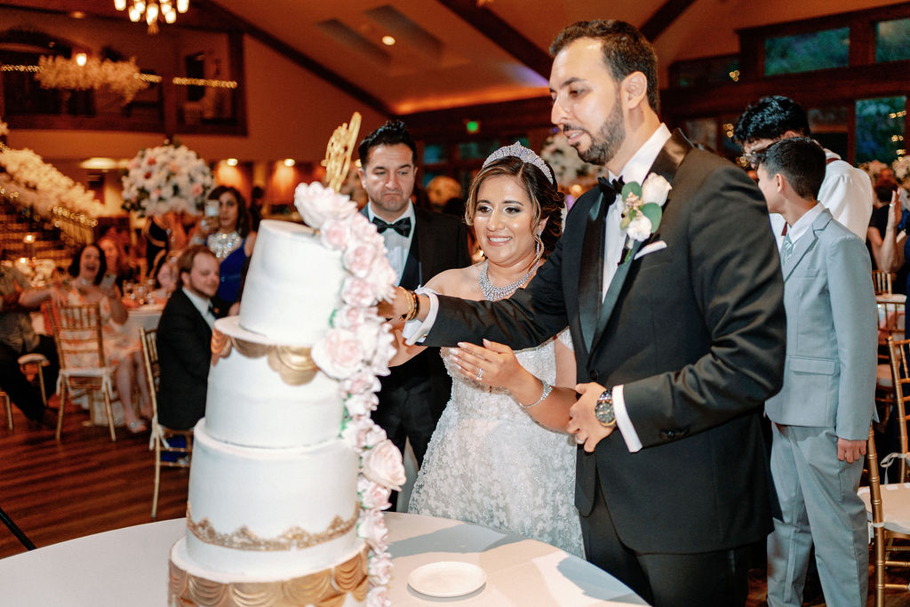 A bride and groom cut their white and gold four tier cake
