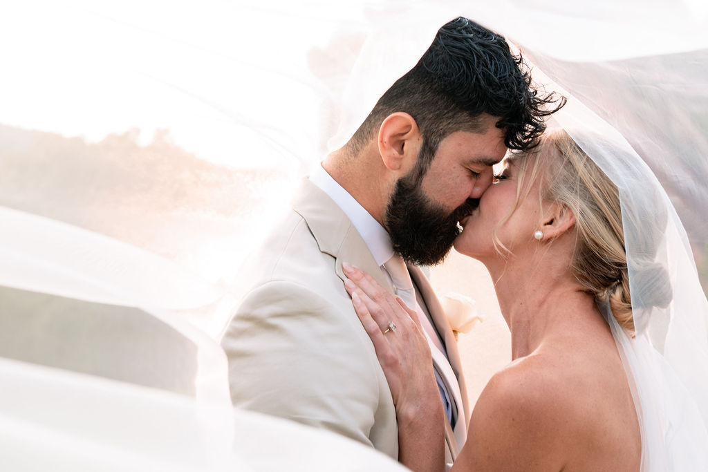 Newlyweds kiss under the veil at sunset