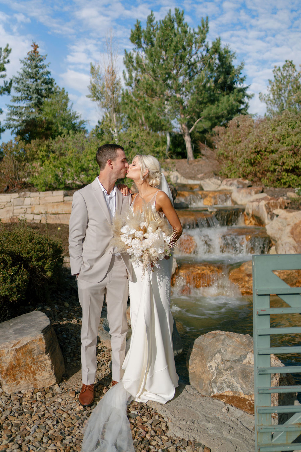 Newlyweds kiss by a water feature