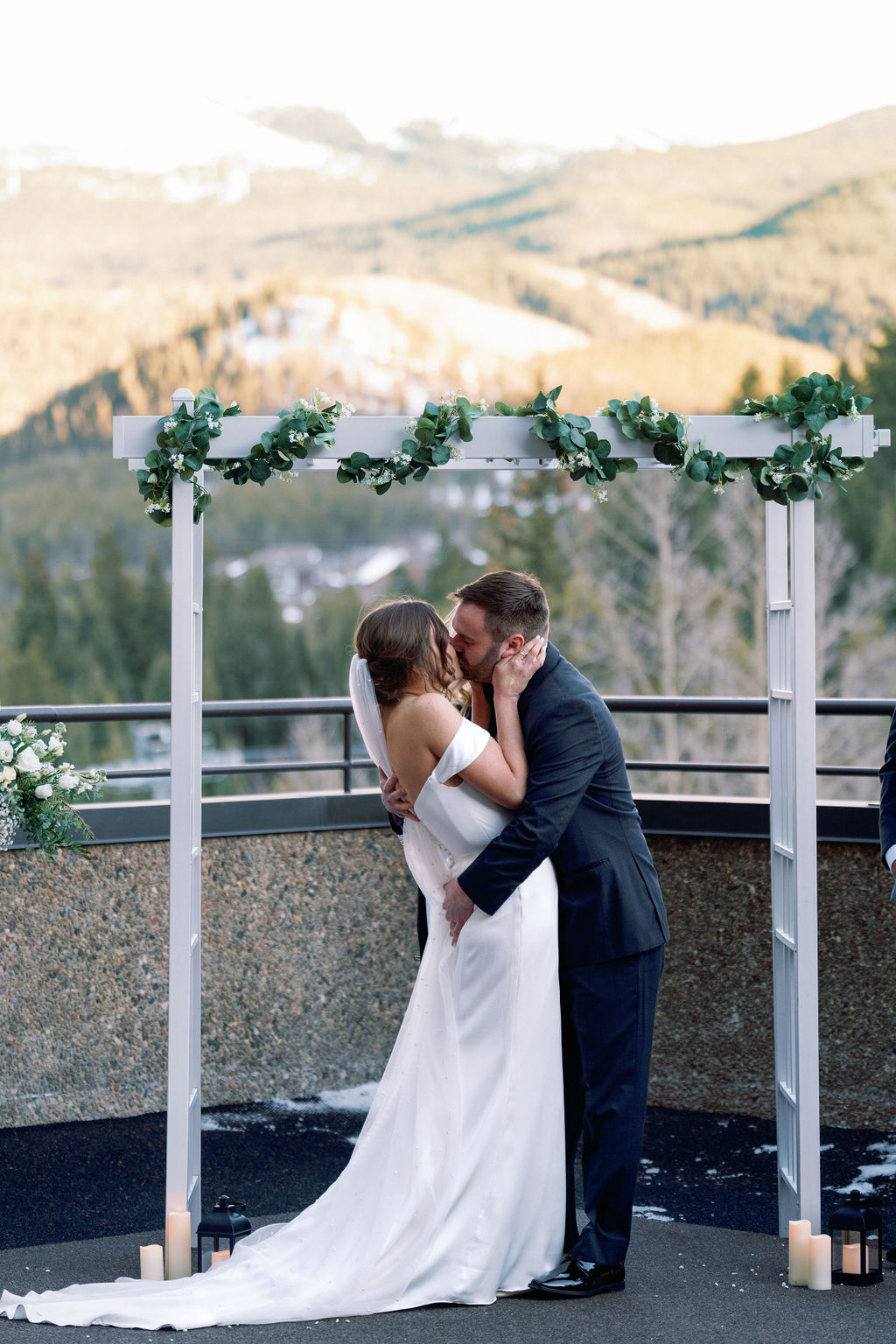 A bride and groom kiss under the ceremony arbor on a mountain overlook at one of the Breckenridge wedding venues