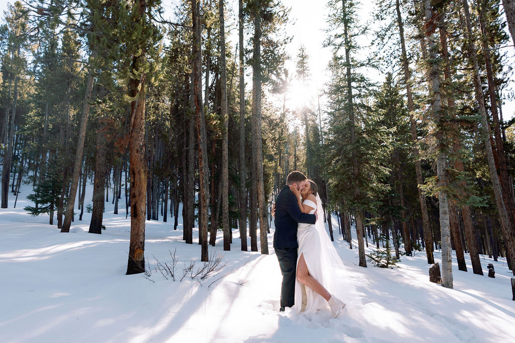 Newlyweds share a passionate kiss in the forest in the snow at one of the Breckenridge wedding venues