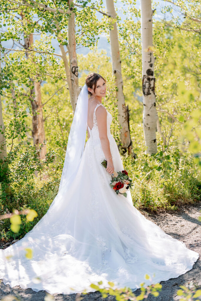 A bride smiles over her shoulder while walking in the aspens at one of the Breckenridge wedding venues