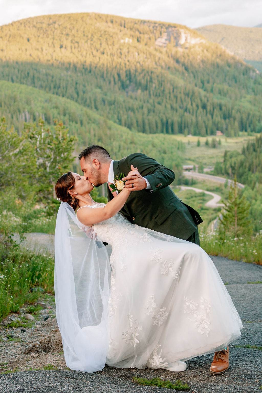 Newlyweds dip and kiss while dancing on a trail at sunset at one of the Breckenridge wedding venues