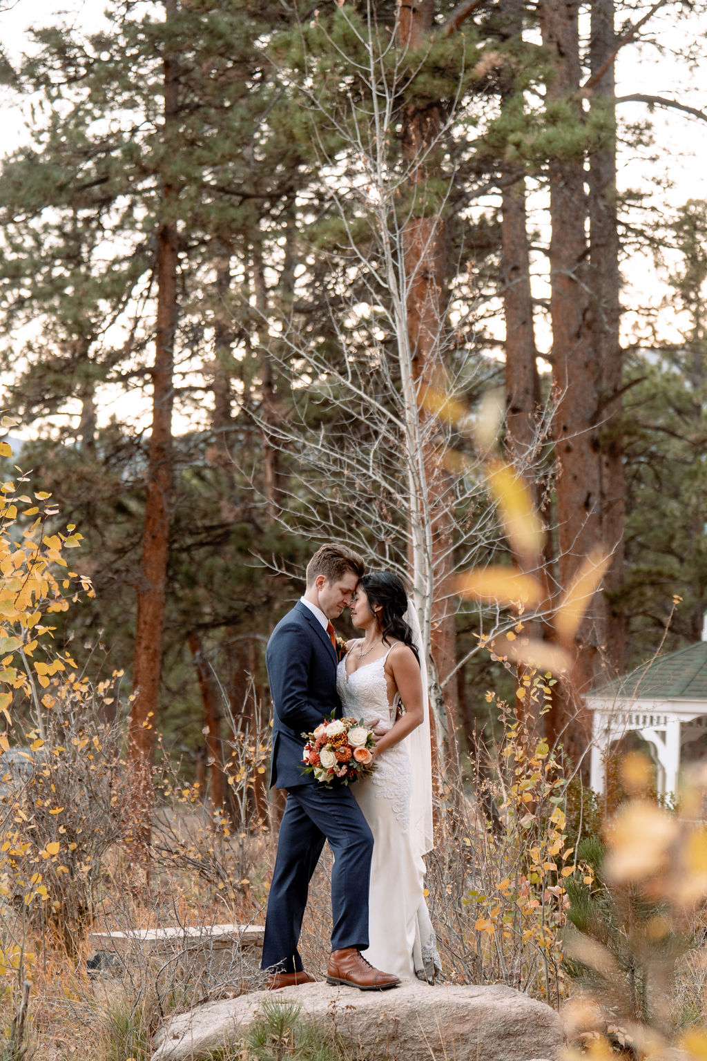 Newlyweds snuggle on a boulder in the gardens of the Della Terra Wedding venue