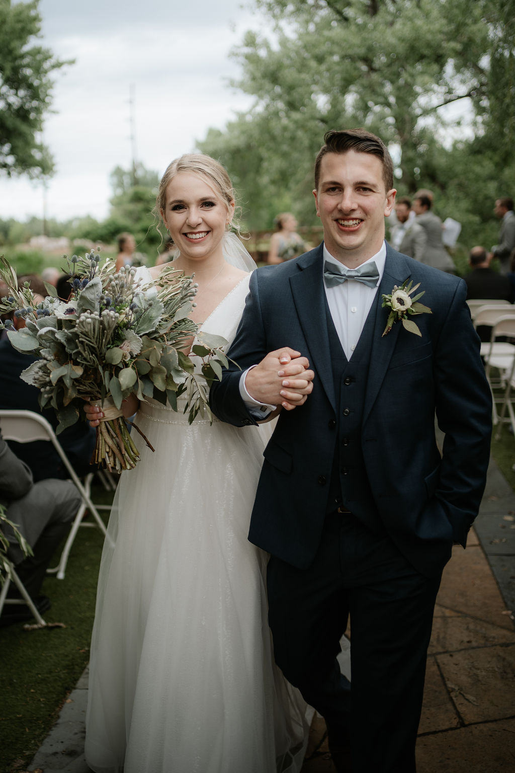 Happy bride and groom holding hands while exiting up the aisle of their hudson gardens wedding ceremony