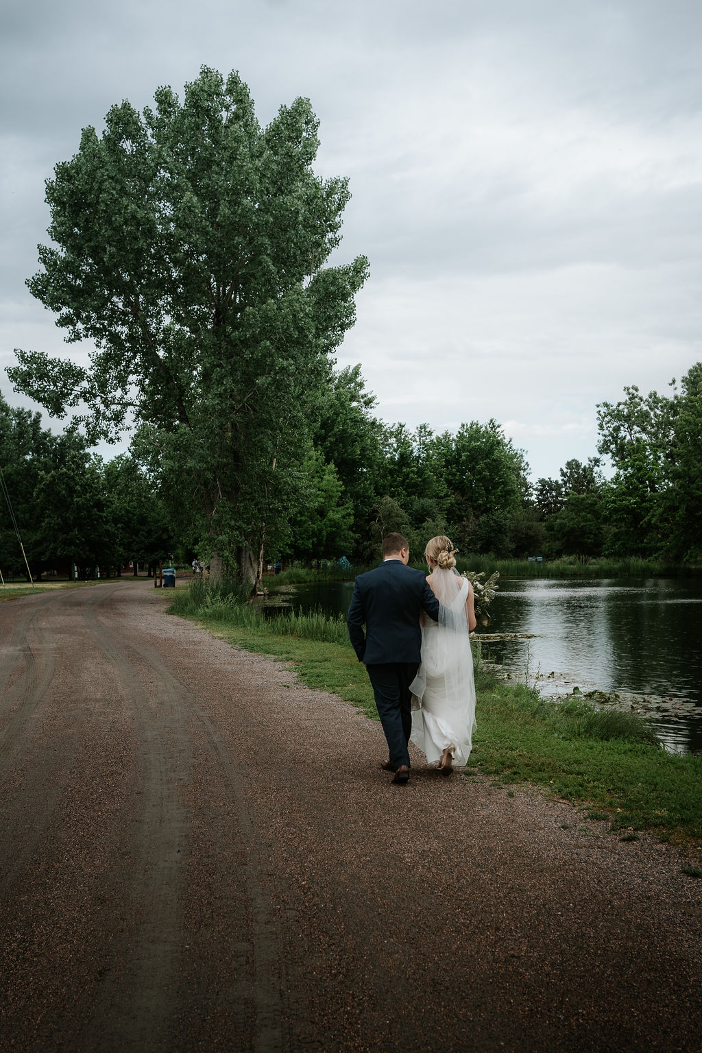 Newlyweds walk closely along the water at their hudson gardens wedding