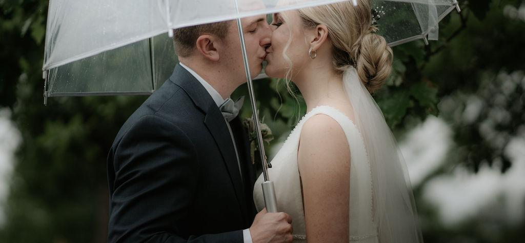 Newlyweds kiss under a clear umbrella