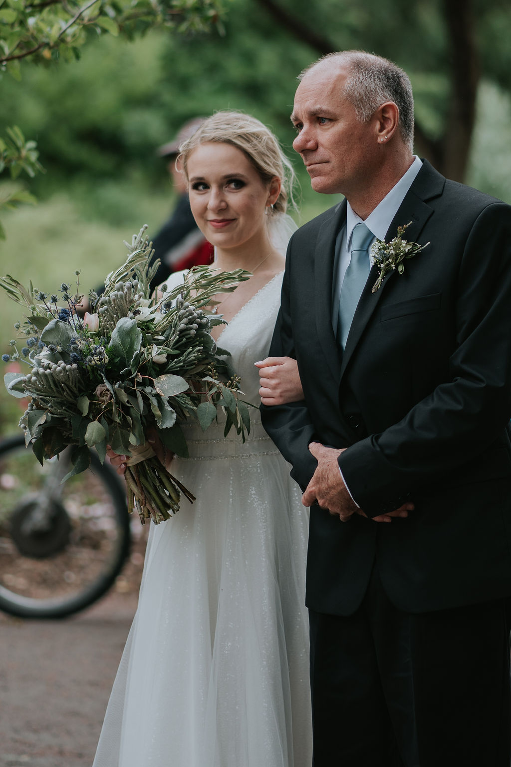 A bride smiles as her dad walks her down the aisle at her hudson gardens wedding