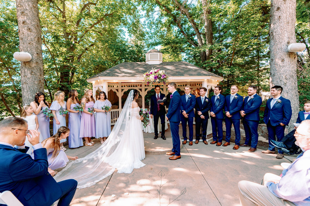 A peek from the aisle of a garden wedding ceremony as the officiant reads