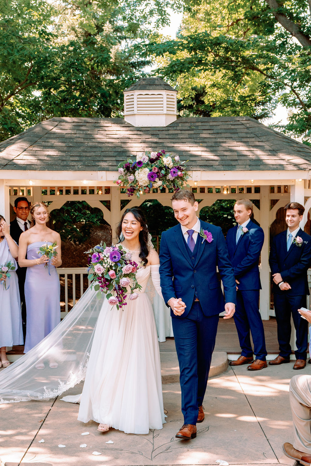 Newlyweds exit up the aisle of their ceremony in the gardens of Tapestry House By Wedgewood Weddings