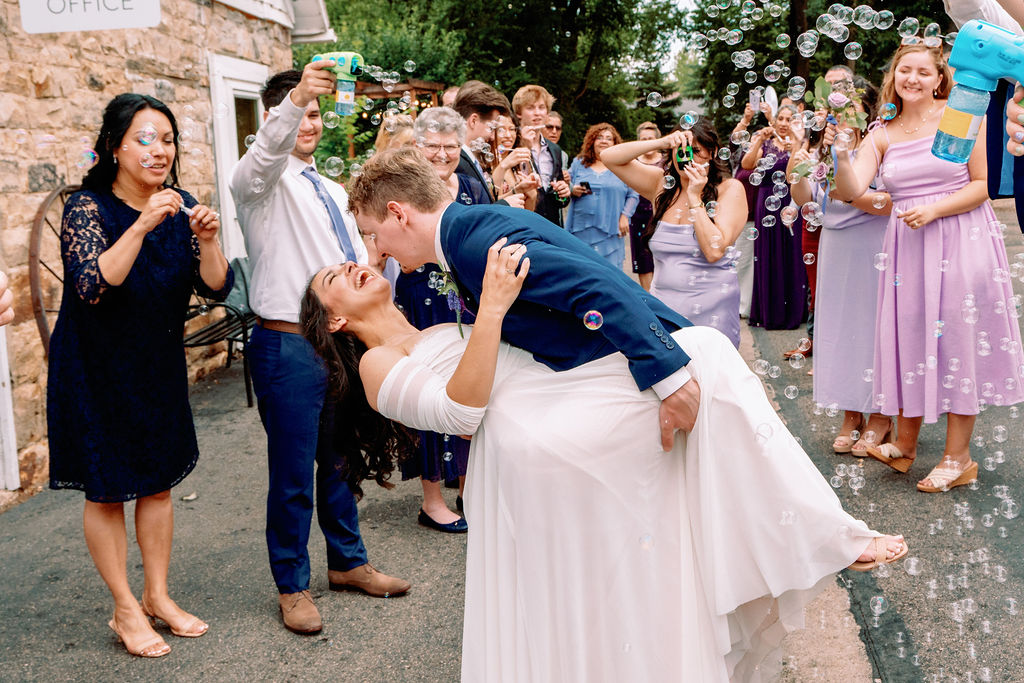 A bride laughs big while being dipped by her groom during a bubble exit from Tapestry House By Wedgewood Weddings