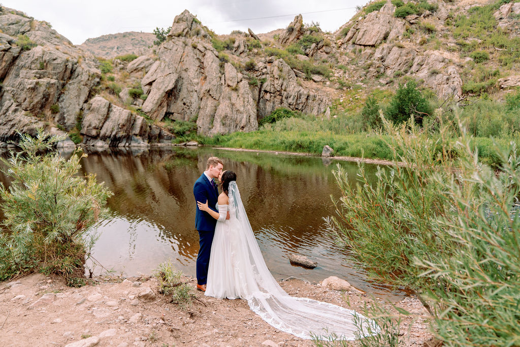 Newlyweds kiss by the pond at heir rustic wedding venue