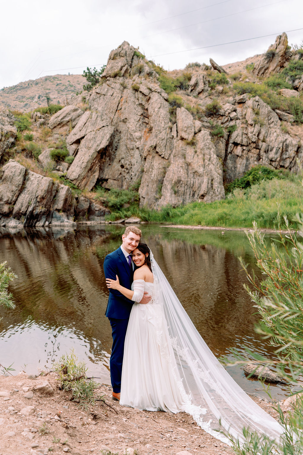 Newlyweds snuggle and smile by the water at Tapestry House By Wedgewood Weddings