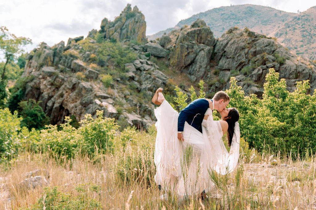 A bride is dipped and kissed while on a hike by her groom at Tapestry House By Wedgewood Weddings