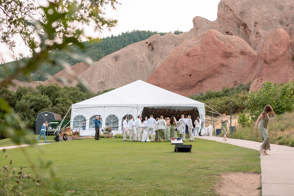 A look at a wedding party by a tent under red rocks on a golf course