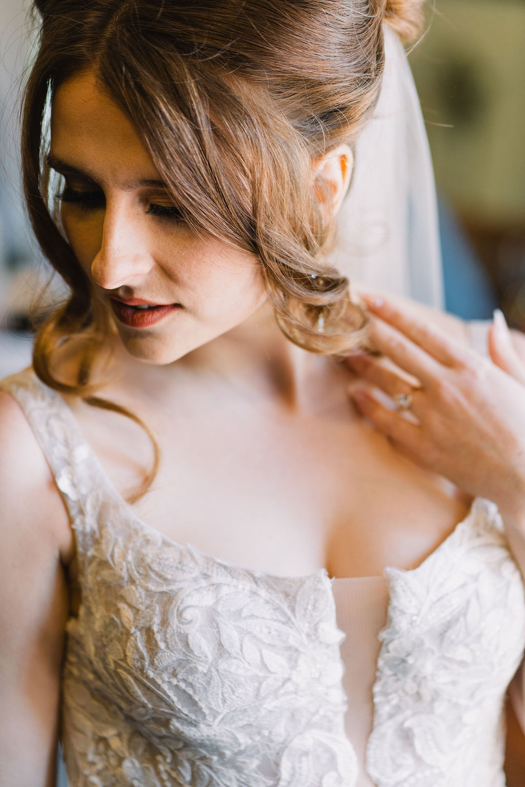 Closeup of a bride pulling back her hair while looking down her shoulder